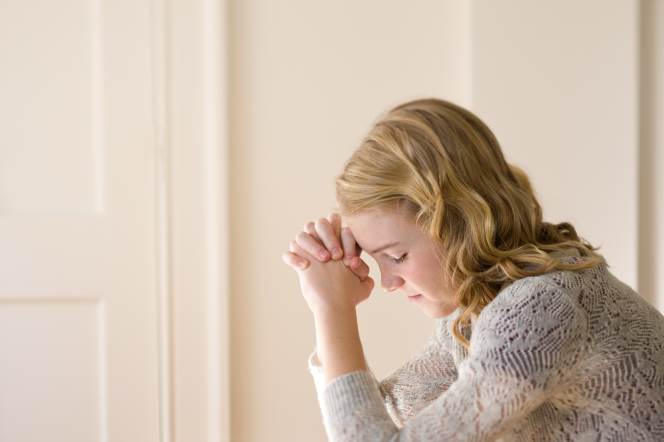 young woman praying on her knees