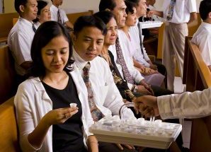 a woman partaking of the sacrament during a sacrament meeting