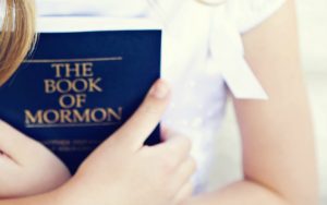A girl holding the Book of Mormon