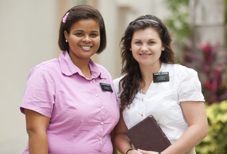 sister missionaries with one sister holding a book