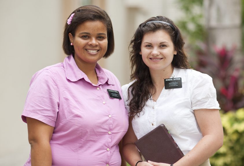sister missionaries with one sister holding a book