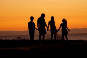 silhouette of a father and his daughters with the sunset in the background