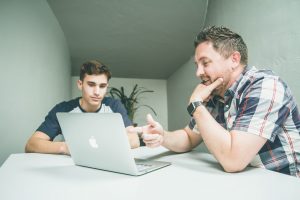 father and son in front of a laptop