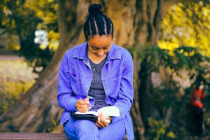 girl reading while sitting in front of a tree