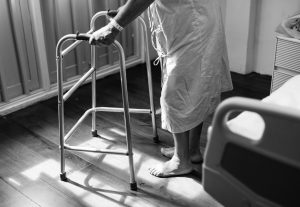 old person on walker in a hospital room