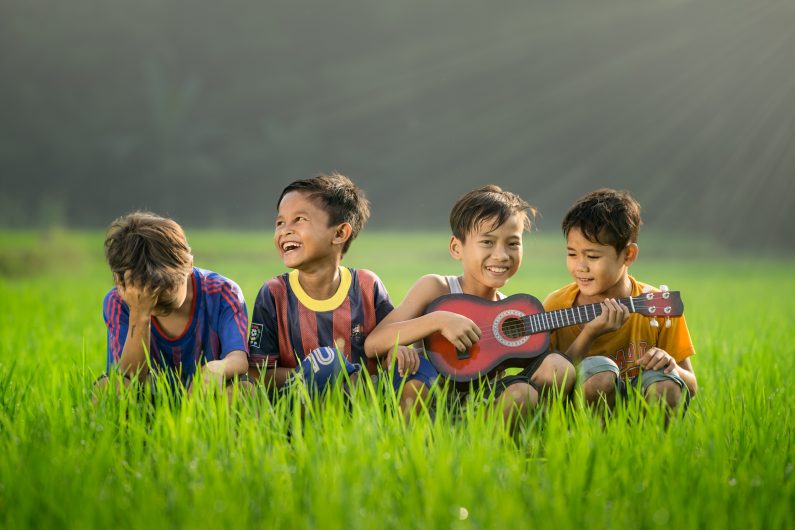 four boys having fun sitting down in rice field