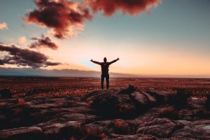 man on top of mountain with arms wide open