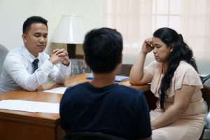 man and woman talking to a man behind the desk