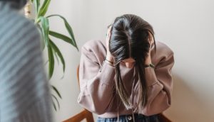 Woman covering her ears to dismiss comments from others.